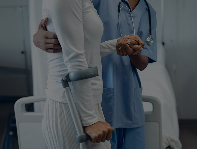 Female doctor helping female patient to walk in the ward at hospital