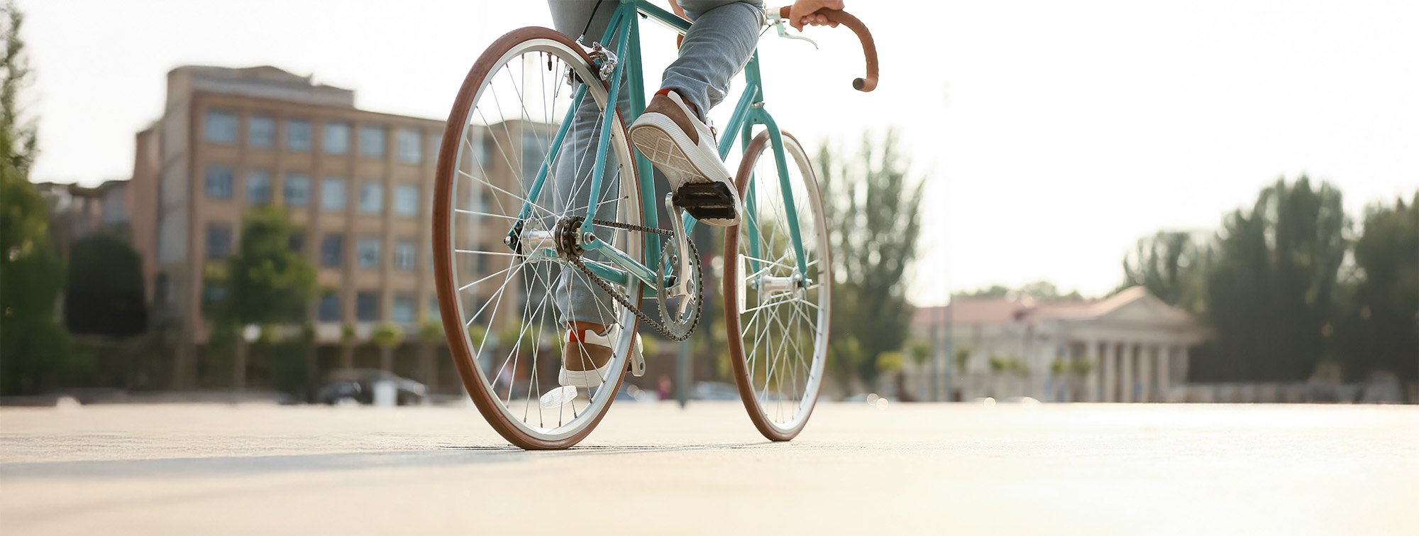 Young man riding bicycle on city square closeup