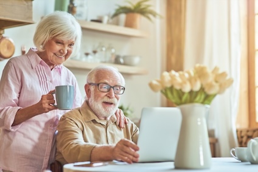 elderly couple smiling at laptop